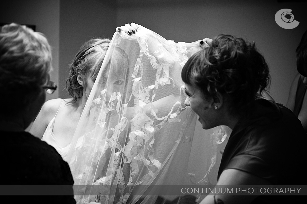 a bride peaks through her the sheer material of one of the layers of her dress