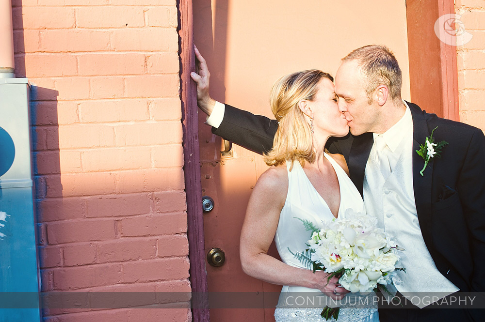 Urban photo of bride and groom kissing outside reception off of Alberta St. in Portlan.